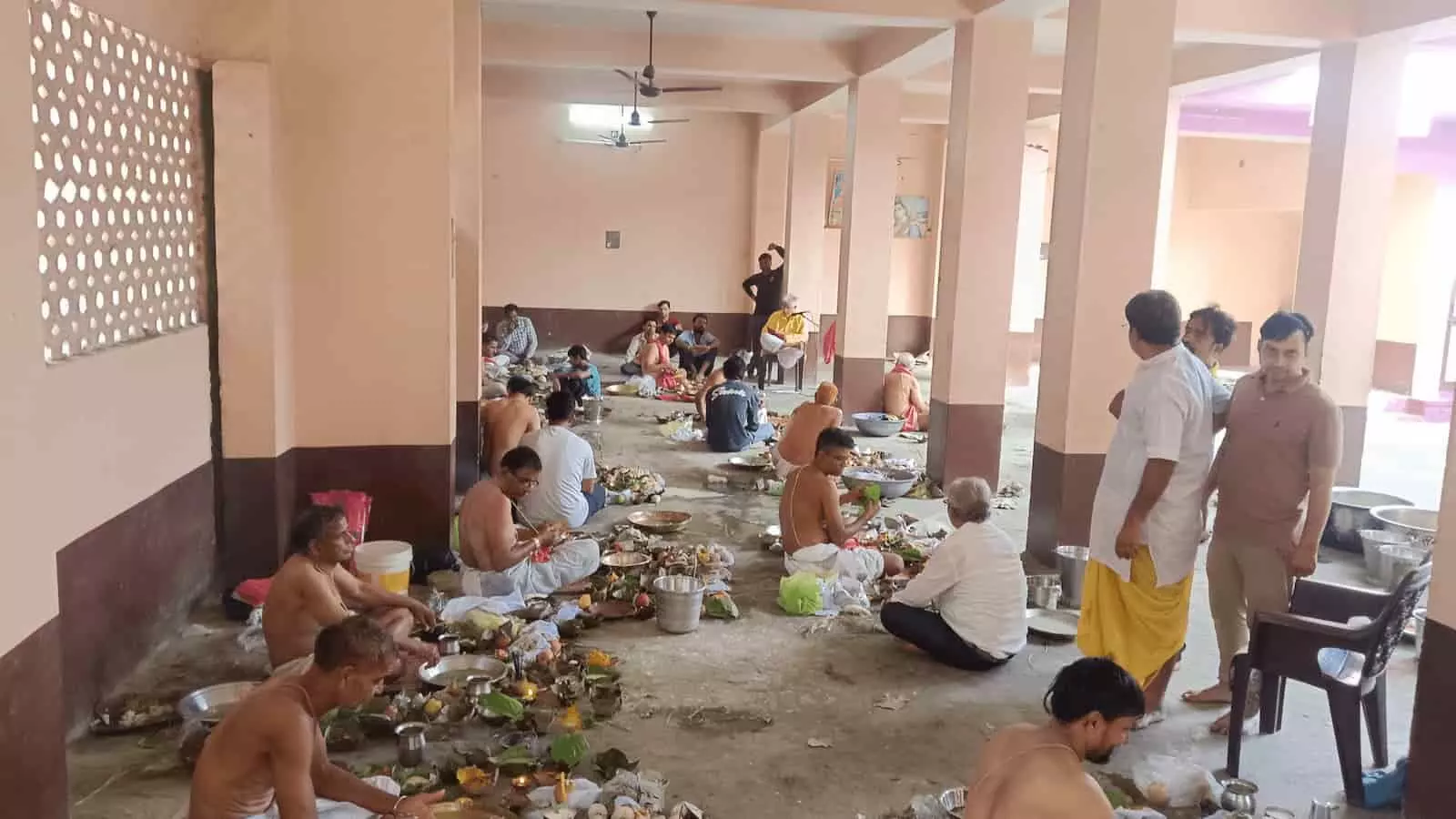 तस्वीर में एक बड़े हॉल के भीतर फर्श पर बैठकर अनुष्ठान और तर्पण करते हुए कई लोग दिखाई दे रहे हैं। तस्वीर में एक बड़े हॉल के भीतर फर्श पर बैठकर अनुष्ठान और तर्पण करते हुए कई लोग दिखाई दे रहे हैं।