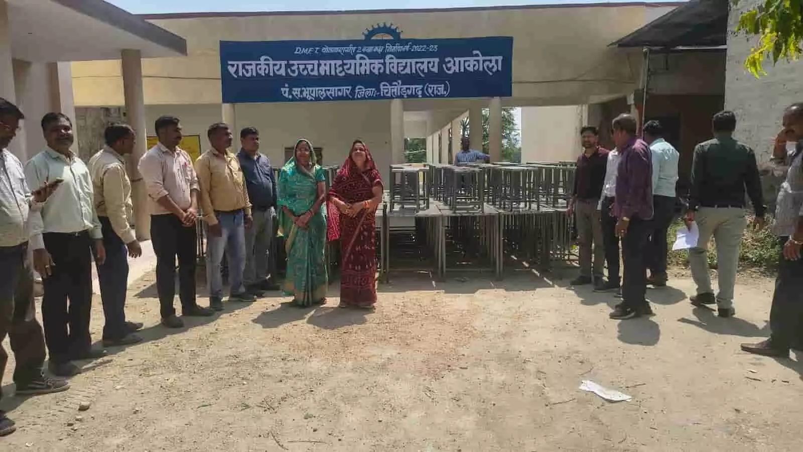 आकोला के राजकीय स्कूल भवन के बाहर 80 टेबल-स्टूल के साथ खड़े प्रधानाचार्य और अन्य लोग। आकोला के राजकीय स्कूल भवन के बाहर 80 टेबल-स्टूल के साथ खड़े प्रधानाचार्य और अन्य लोग।