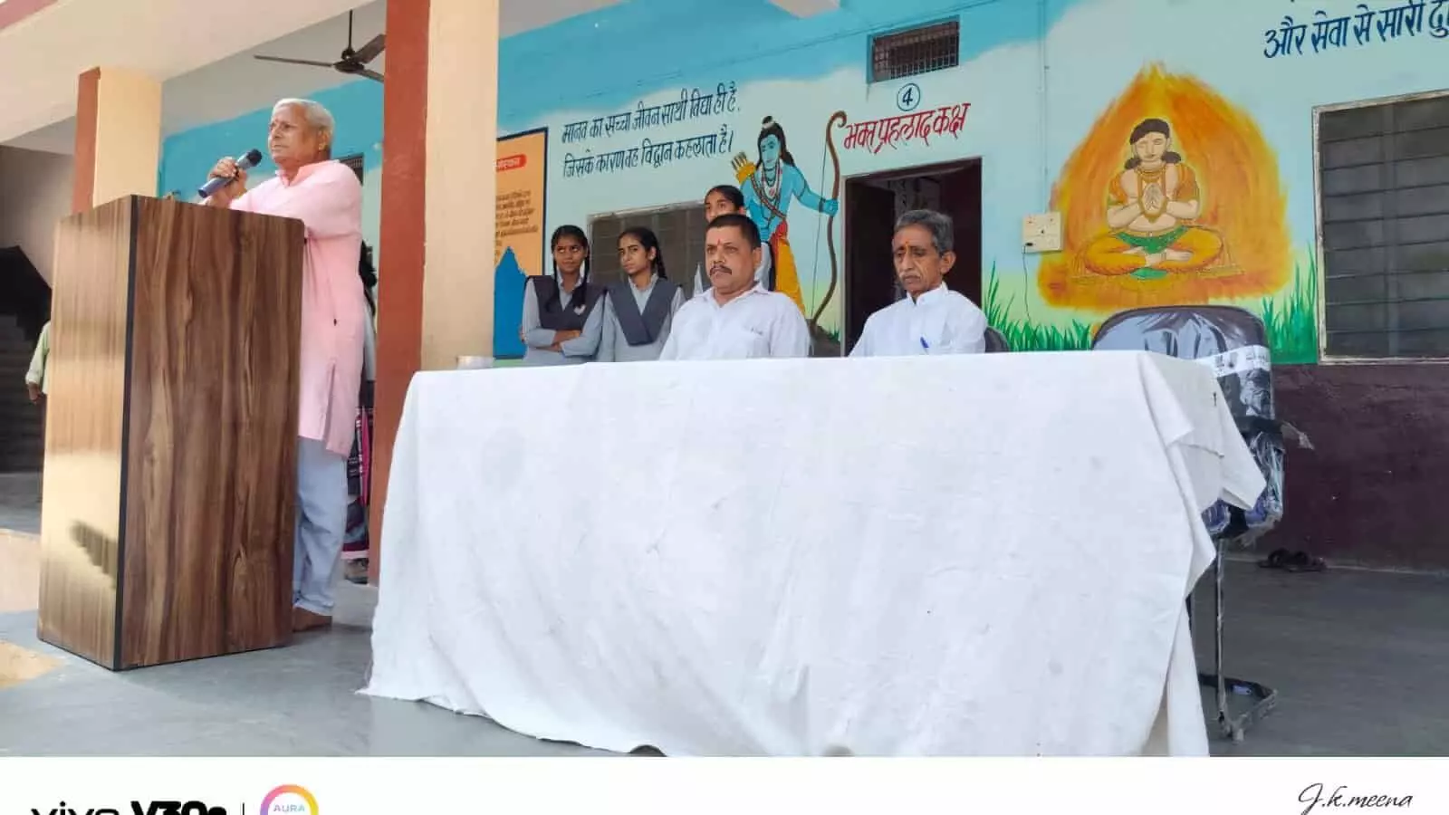 खेरवाड़ा के विद्यालय में आयोजित कार्यक्रम के मंच पर माइक से बोलते व्यक्ति और पास बैठे अन्य लोग। खेरवाड़ा के विद्यालय में आयोजित कार्यक्रम के मंच पर माइक से बोलते व्यक्ति और पास बैठे अन्य लोग।