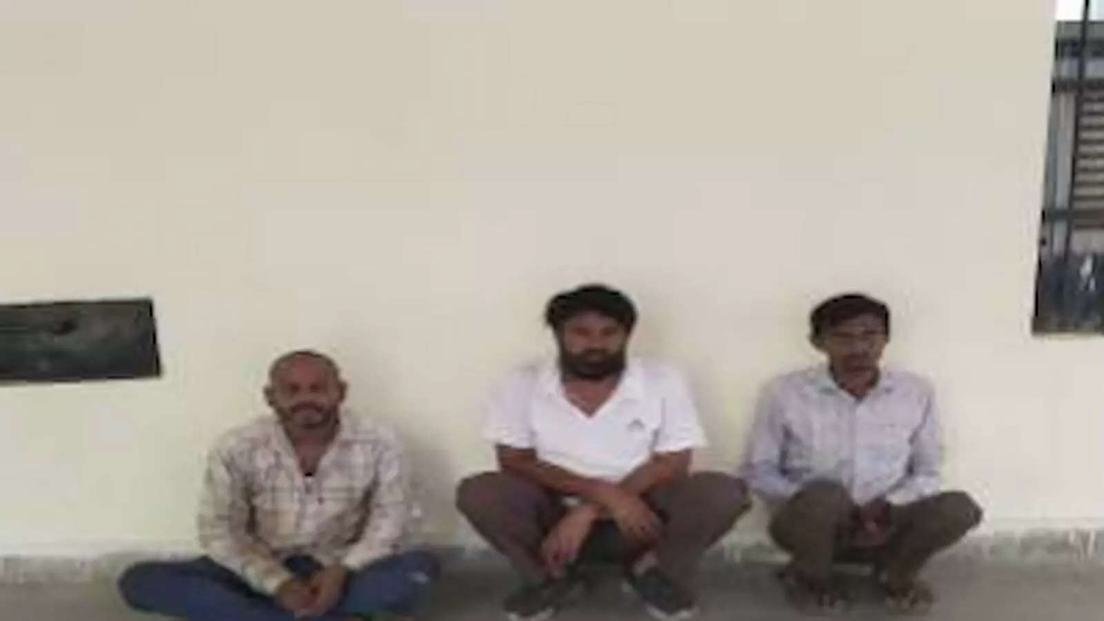 तस्वीर में तीन गिरफ्तार वारंटी जमीन पर बैठे हुए दिखाई दे रहे हैं। तस्वीर में तीन गिरफ्तार वारंटी जमीन पर बैठे हुए दिखाई दे रहे हैं।