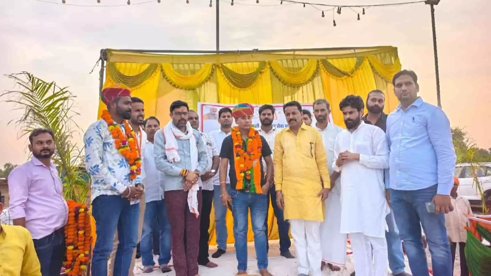 बारां में आयोजित सेवा संकल्प यात्रा के मंच पर कई लोग पारंपरिक साफा और माला पहने खड़े हैं। बारां में आयोजित सेवा संकल्प यात्रा के मंच पर कई लोग पारंपरिक साफा और माला पहने खड़े हैं।