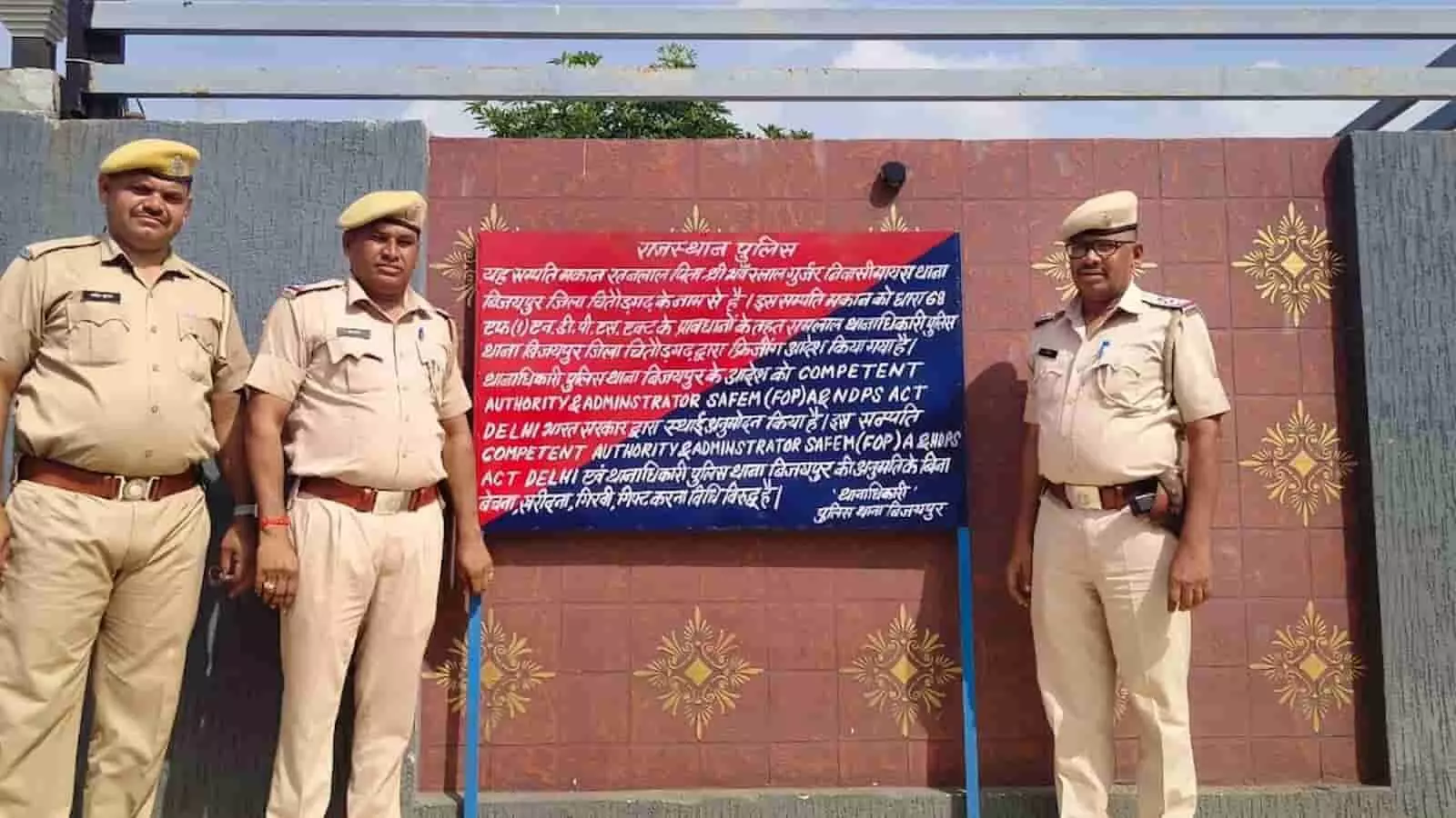 तस्वीर में बिजयपुर थाने के पुलिसकर्मी चित्तौड़गढ़ में एनडीपीएस मामले के आरोपी की कुर्क की गई संपत्ति के बाहर लगे बोर्ड के पास खड़े हैं। तस्वीर में बिजयपुर थाने के पुलिसकर्मी चित्तौड़गढ़ में एनडीपीएस मामले के आरोपी की कुर्क की गई संपत्ति के बाहर लगे बोर्ड के पास खड़े हैं।