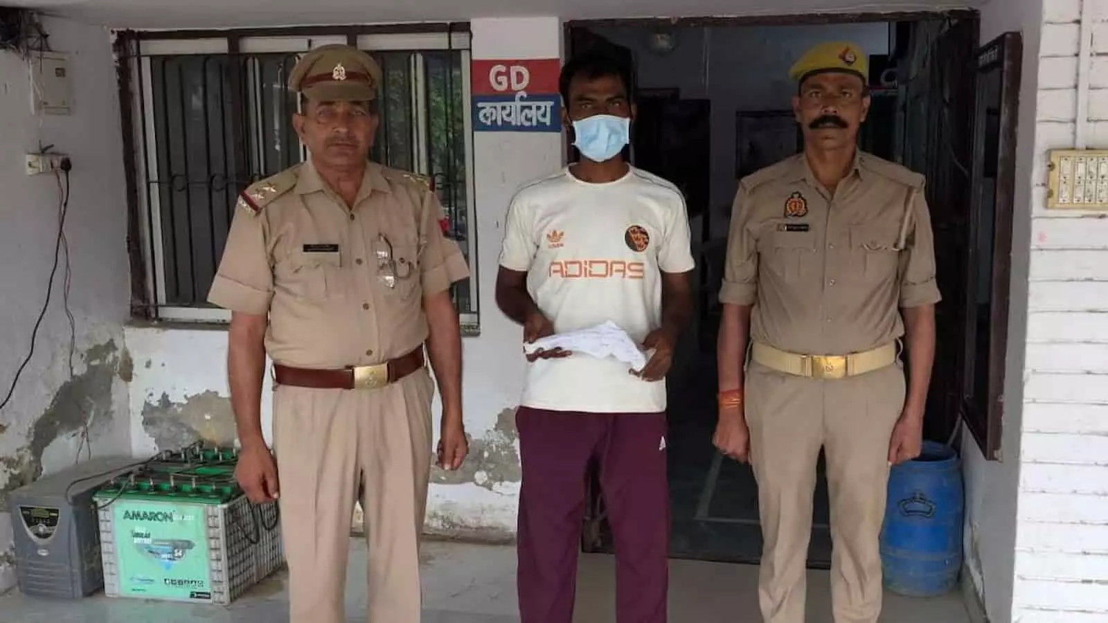 धौलाना थाने के बाहर दो पुलिसकर्मियों के बीच खड़ा मास्क पहना हुआ अभियुक्त। धौलाना थाने के बाहर दो पुलिसकर्मियों के बीच खड़ा मास्क पहना हुआ अभियुक्त।