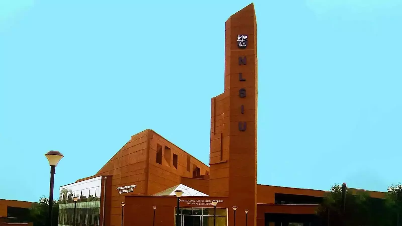 तस्वीर में NLSIU बेंगलुरु परिसर की मुख्य लाल ईंटों वाली इमारत और पुस्तकालय टॉवर दिख रहा है। तस्वीर में NLSIU बेंगलुरु परिसर की मुख्य लाल ईंटों वाली इमारत और पुस्तकालय टॉवर दिख रहा है।