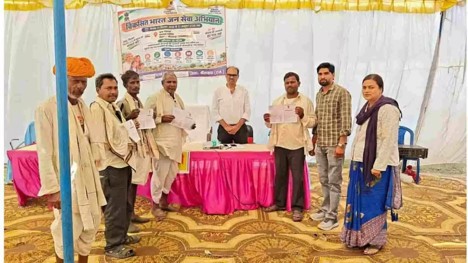 तस्वीर में जन सेवा शिविर के बैनर तले अधिकारी और ग्रामीण किसान कार्ड के साथ खड़े हैं। तस्वीर में जन सेवा शिविर के बैनर तले अधिकारी और ग्रामीण किसान कार्ड के साथ खड़े हैं।