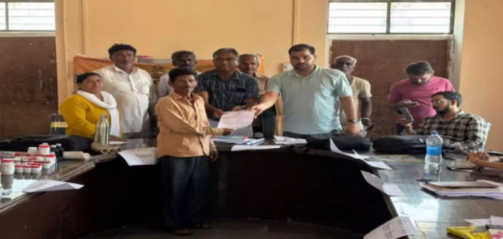 तस्वीर में एक अधिकारी ग्रामीण व्यक्ति को प्रमाण पत्र सौंपते हुए और अन्य लोग उपस्थित दिख रहे हैं। तस्वीर में एक अधिकारी ग्रामीण व्यक्ति को प्रमाण पत्र सौंपते हुए और अन्य लोग उपस्थित दिख रहे हैं।