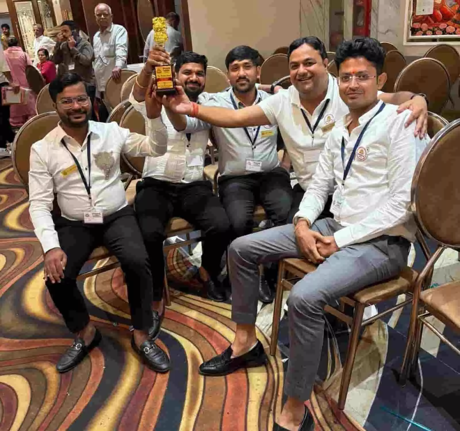 तस्वीर में दिख रही हॉल की कुर्सियों पर बैठे एपेक्स क्लब के सदस्य ट्रॉफी पकड़े हुए हैं। तस्वीर में दिख रही हॉल की कुर्सियों पर बैठे एपेक्स क्लब के सदस्य ट्रॉफी पकड़े हुए हैं।