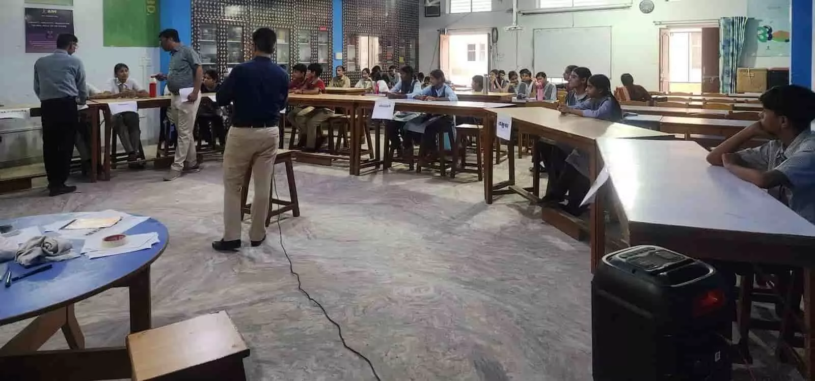 सवाई माधोपुर के एक विद्यालय हॉल में मेजों पर बैठे छात्र-छात्राएं प्रतियोगिता में शामिल होते दिख रहे हैं। सवाई माधोपुर के एक विद्यालय हॉल में मेजों पर बैठे छात्र-छात्राएं प्रतियोगिता में शामिल होते दिख रहे हैं।
