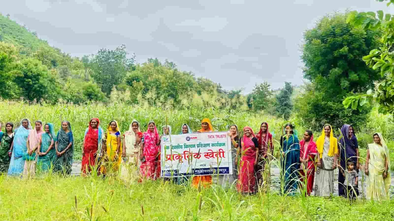 तस्वीर में सुवेरी के हरे-भरे खेत में महिला किसान एक बैनर पकड़कर साथ में खड़ी हैं। तस्वीर में सुवेरी के हरे-भरे खेत में महिला किसान एक बैनर पकड़कर साथ में खड़ी हैं।