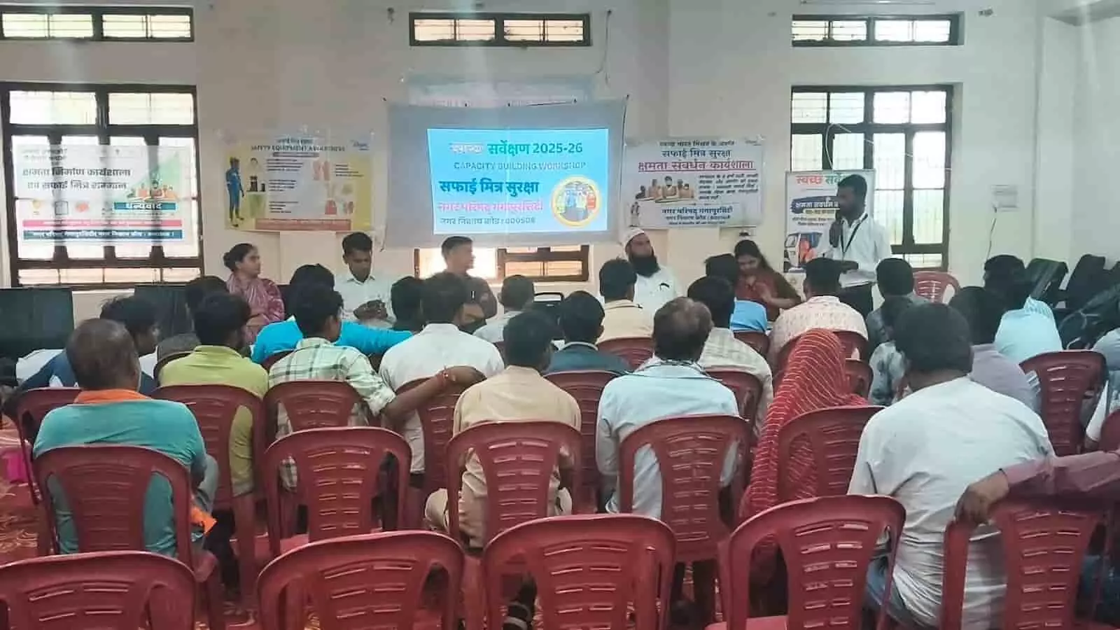 गंगापुर सिटी नगर परिषद् सभागार में प्रोजेक्टर के सामने बैठे लोग और संबोधित करता एक व्यक्ति। गंगापुर सिटी नगर परिषद् सभागार में प्रोजेक्टर के सामने बैठे लोग और संबोधित करता एक व्यक्ति।