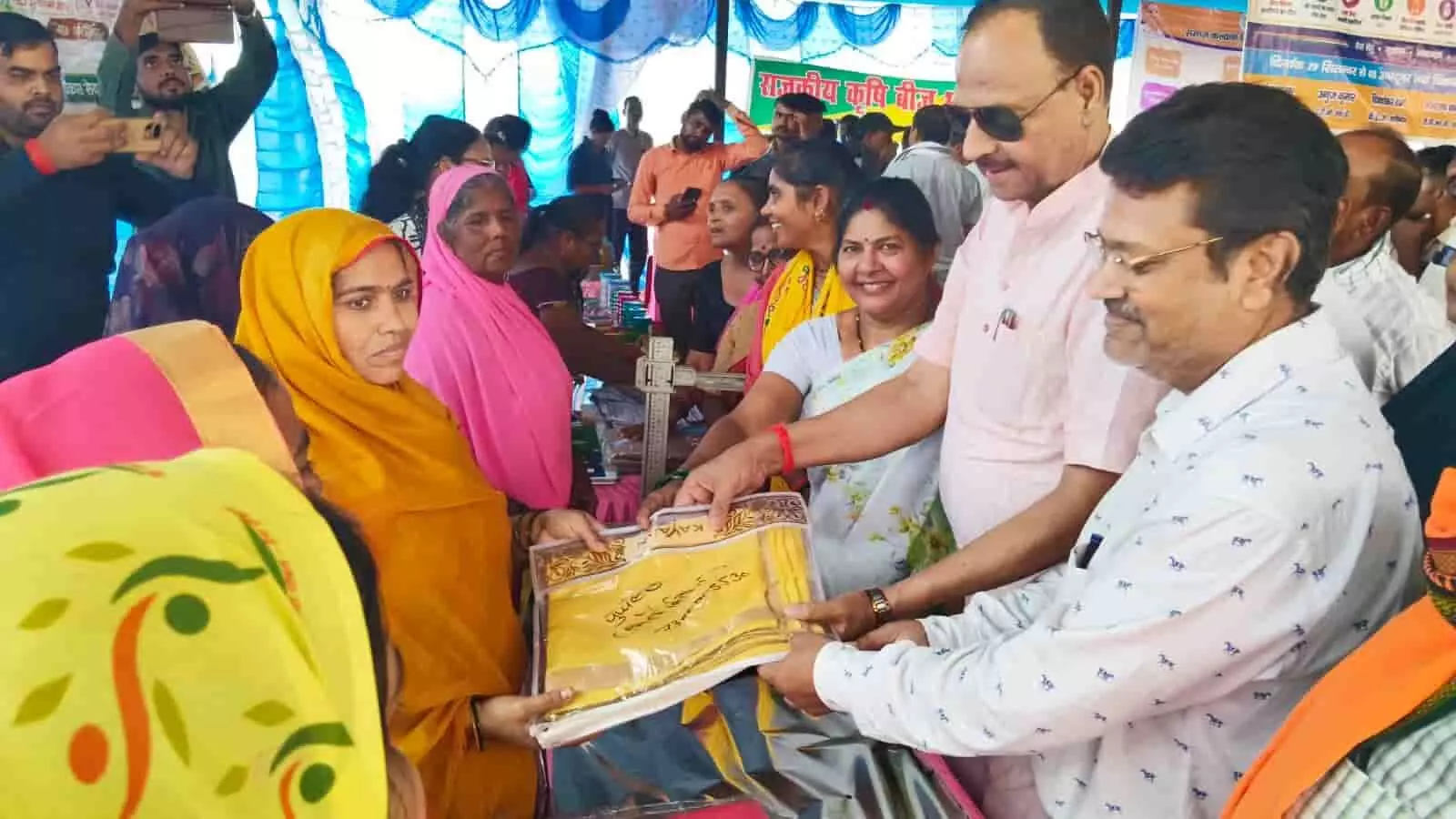 तस्वीर में दिख रही महिला को विधायक और अधिकारी स्टॉल पर साड़ी सौंपते हुए नजर आ रहे हैं। तस्वीर में दिख रही महिला को विधायक और अधिकारी स्टॉल पर साड़ी सौंपते हुए नजर आ रहे हैं।