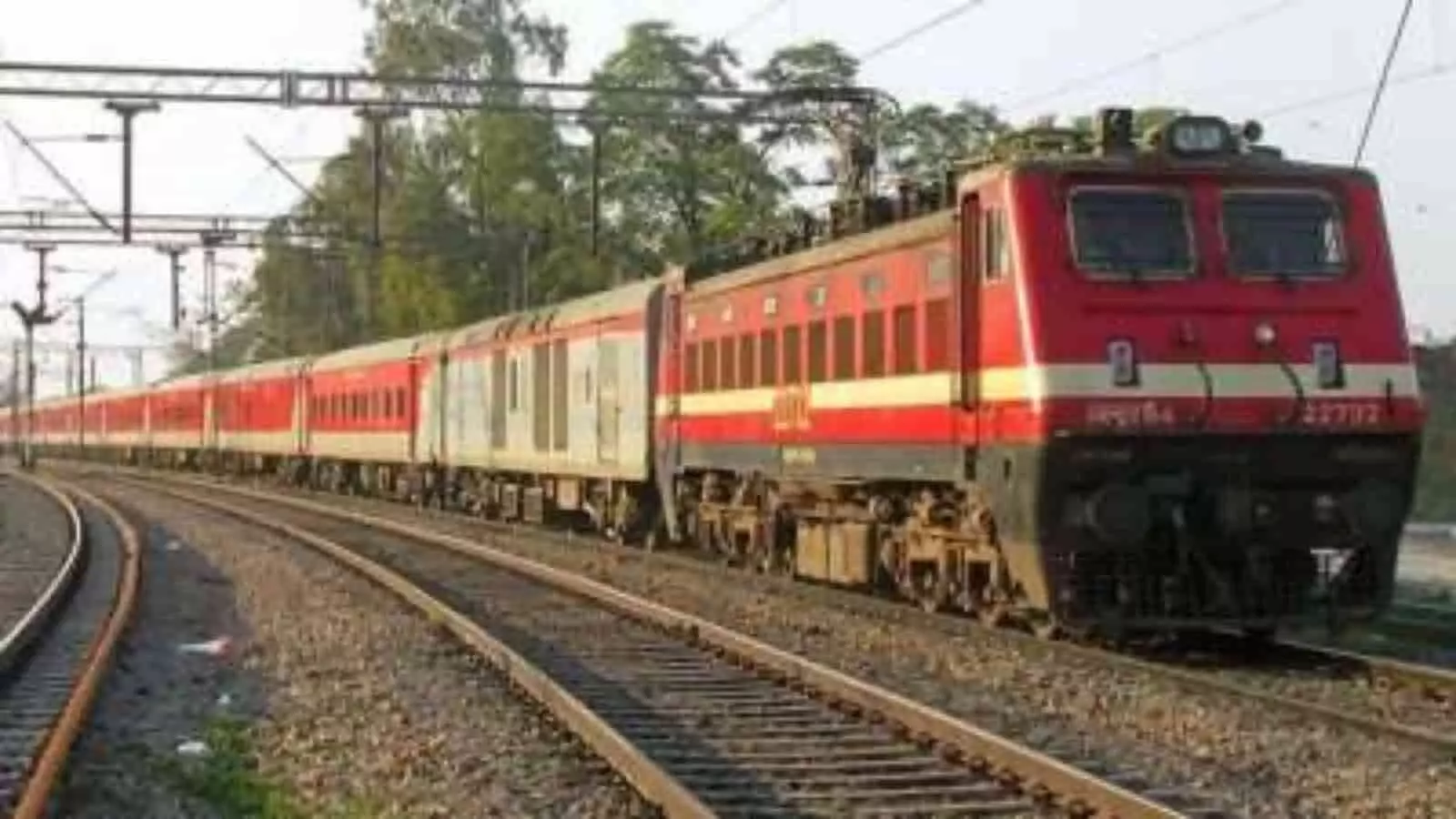 तस्वीर में पटरियों पर चलती हुई एक लाल रंग की भारतीय रेलवे की एक्सप्रेस ट्रेन दिख रही है। तस्वीर में पटरियों पर चलती हुई एक लाल रंग की भारतीय रेलवे की एक्सप्रेस ट्रेन दिख रही है।