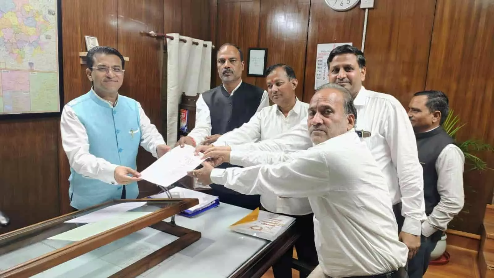 तस्वीर में दिख रहे वकील बाईं ओर बैठे व्यक्ति को दस्तावेज और ज्ञापन सौंप रहे हैं। तस्वीर में दिख रहे वकील बाईं ओर बैठे व्यक्ति को दस्तावेज और ज्ञापन सौंप रहे हैं।