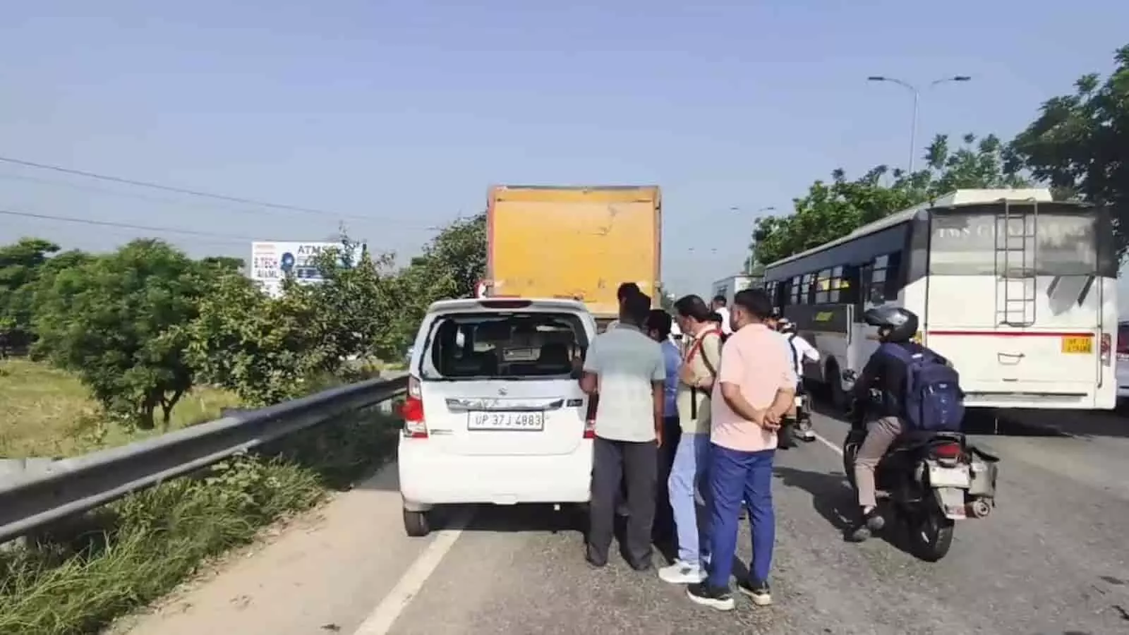 तस्वीर में दिख रहे लोग हापुड़ हाईवे पर दुर्घटनाग्रस्त सफेद कार के पास खड़े हैं। तस्वीर में दिख रहे लोग हापुड़ हाईवे पर दुर्घटनाग्रस्त सफेद कार के पास खड़े हैं।