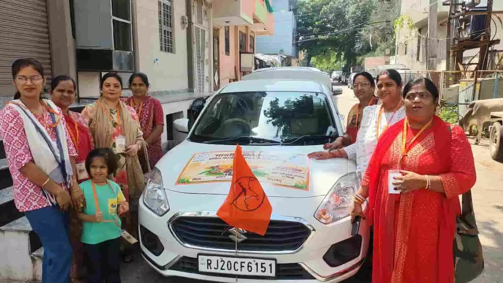 तस्वीर में महिला कार्यकर्ता एक सजाई गई सफेद कार के पास खड़ी हैं। तस्वीर में महिला कार्यकर्ता एक सजाई गई सफेद कार के पास खड़ी हैं।