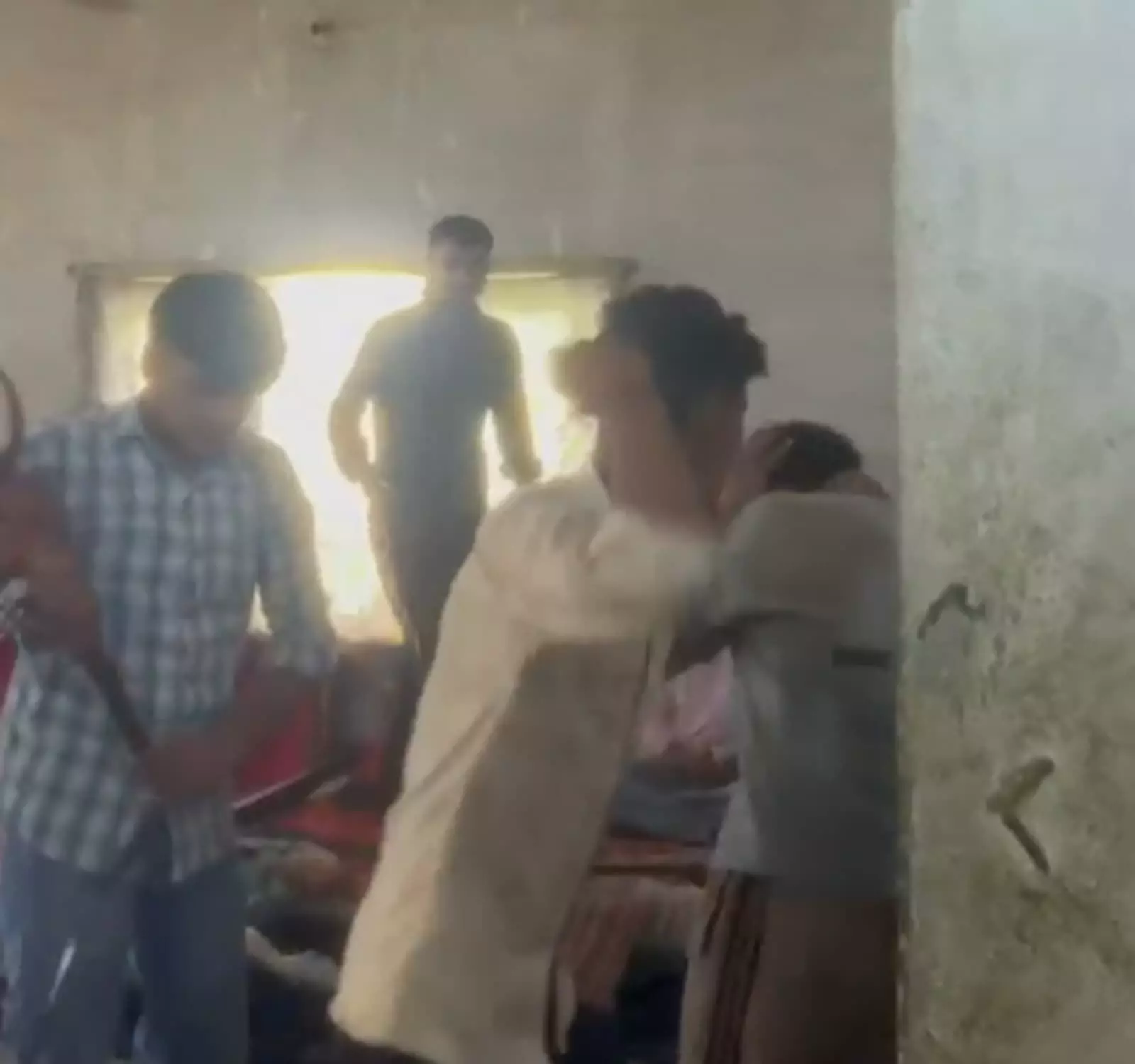 तस्वीर में बाएं से दाएं खड़े कुछ पुरुष एक कमरे में युवक पर हाथ उठा रहे हैं। तस्वीर में बाएं से दाएं खड़े कुछ पुरुष एक कमरे में युवक पर हाथ उठा रहे हैं।