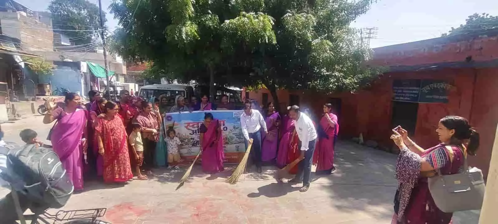 तस्वीर में आंगनबाड़ी केंद्र परिसर के बाहर महिलाएं बैनर के साथ झाड़ू लगाकर सफाई करती दिख रही हैं। तस्वीर में आंगनबाड़ी केंद्र परिसर के बाहर महिलाएं बैनर के साथ झाड़ू लगाकर सफाई करती दिख रही हैं।