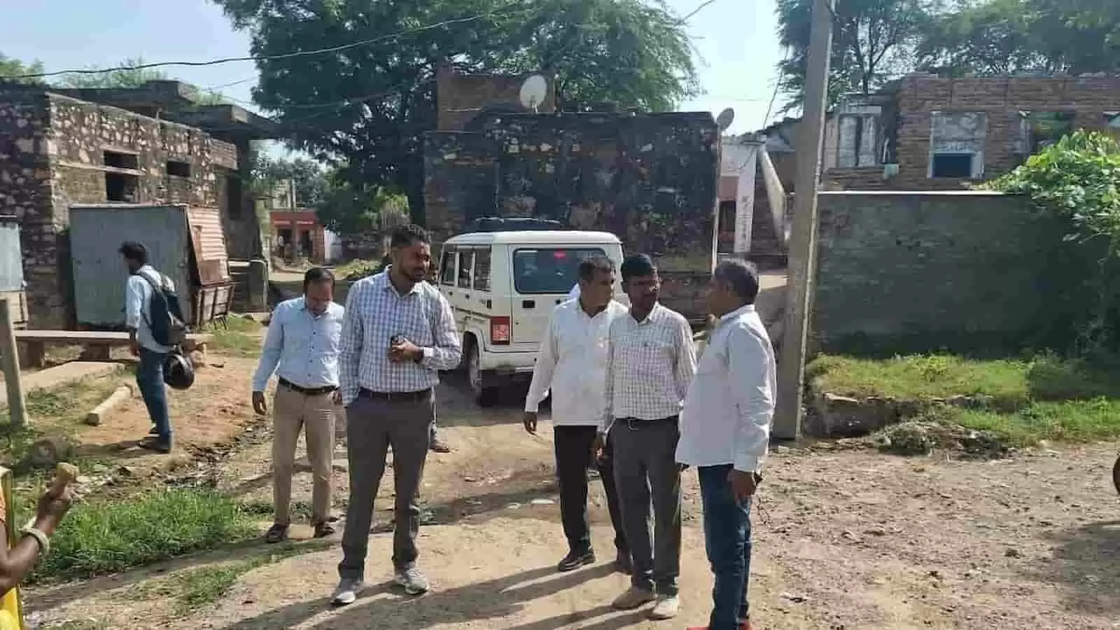 तस्वीर में दिख रही गांव की सड़क पर खड़े अधिकारी और स्थानीय लोग आपस में बात कर रहे हैं। तस्वीर में दिख रही गांव की सड़क पर खड़े अधिकारी और स्थानीय लोग आपस में बात कर रहे हैं।