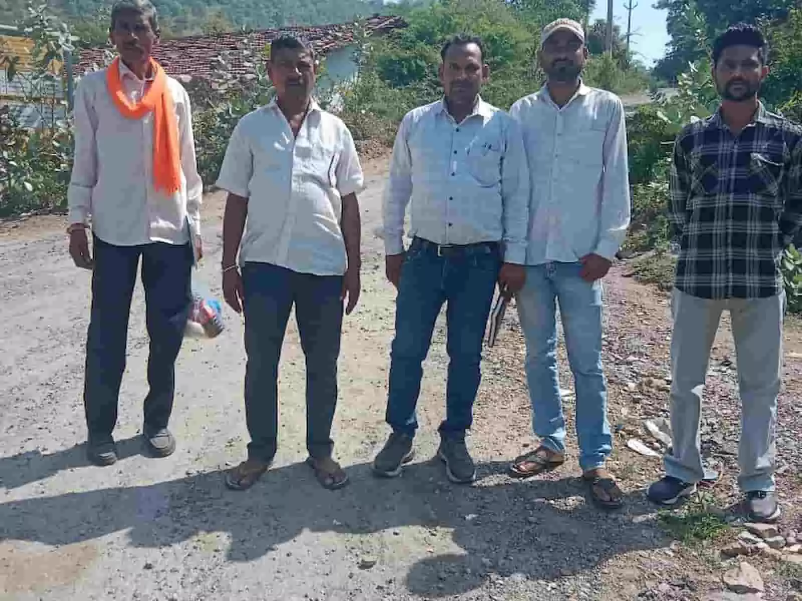 तस्वीर में बाएं से दाएं खड़े पांच पुरुष ग्रामीण इलाके की कच्ची सड़क पर निरीक्षण के दौरान मौजूद हैं। तस्वीर में बाएं से दाएं खड़े पांच पुरुष ग्रामीण इलाके की कच्ची सड़क पर निरीक्षण के दौरान मौजूद हैं।