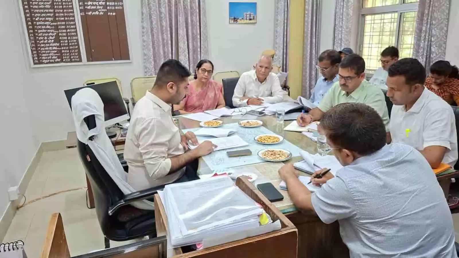 तस्वीर में बाईं ओर जिला कलक्टर और अन्य प्रशासनिक अधिकारी मेज के चारों ओर बैठकर चर्चा कर रहे हैं। तस्वीर में बाईं ओर जिला कलक्टर और अन्य प्रशासनिक अधिकारी मेज के चारों ओर बैठकर चर्चा कर रहे हैं।