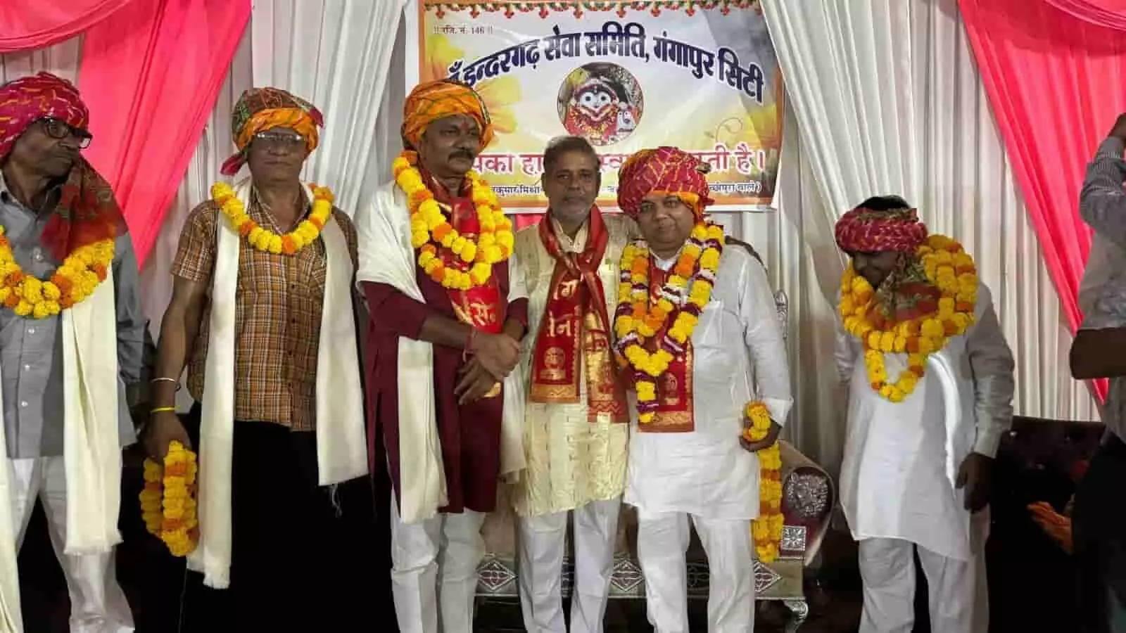 तस्वीर में इन्द्रगढ़ सेवा समिति बैनर के आगे साफा और फूलों की माला पहने पुरुष खड़े हैं। तस्वीर में इन्द्रगढ़ सेवा समिति बैनर के आगे साफा और फूलों की माला पहने पुरुष खड़े हैं।