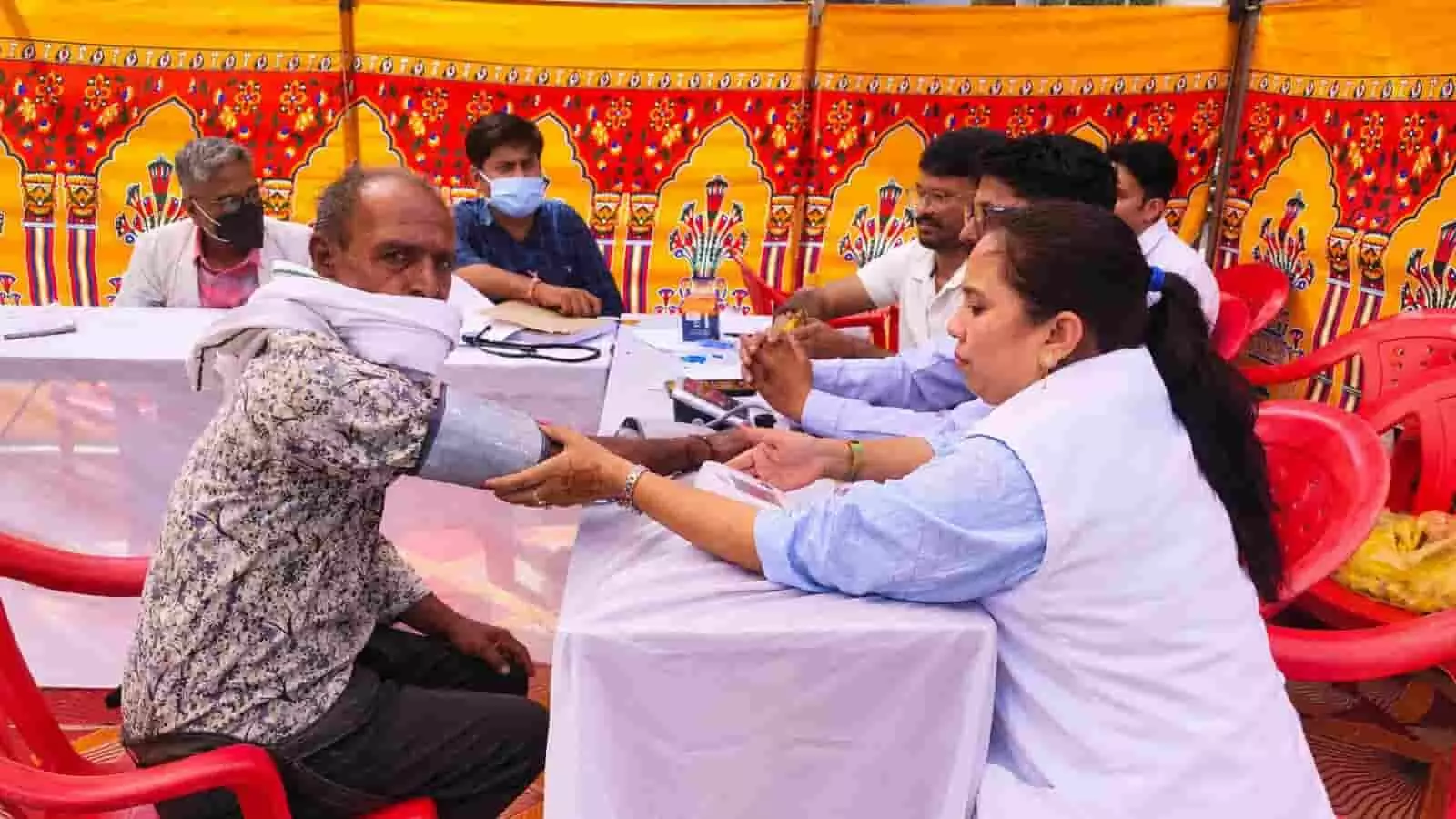 तस्वीर में बाएं से एक बुजुर्ग व्यक्ति बैठा है और दाएं बैठी महिला डॉक्टर उसका ब्लड प्रेशर जांच रही है। तस्वीर में बाएं से एक बुजुर्ग व्यक्ति बैठा है और दाएं बैठी महिला डॉक्टर उसका ब्लड प्रेशर जांच रही है।