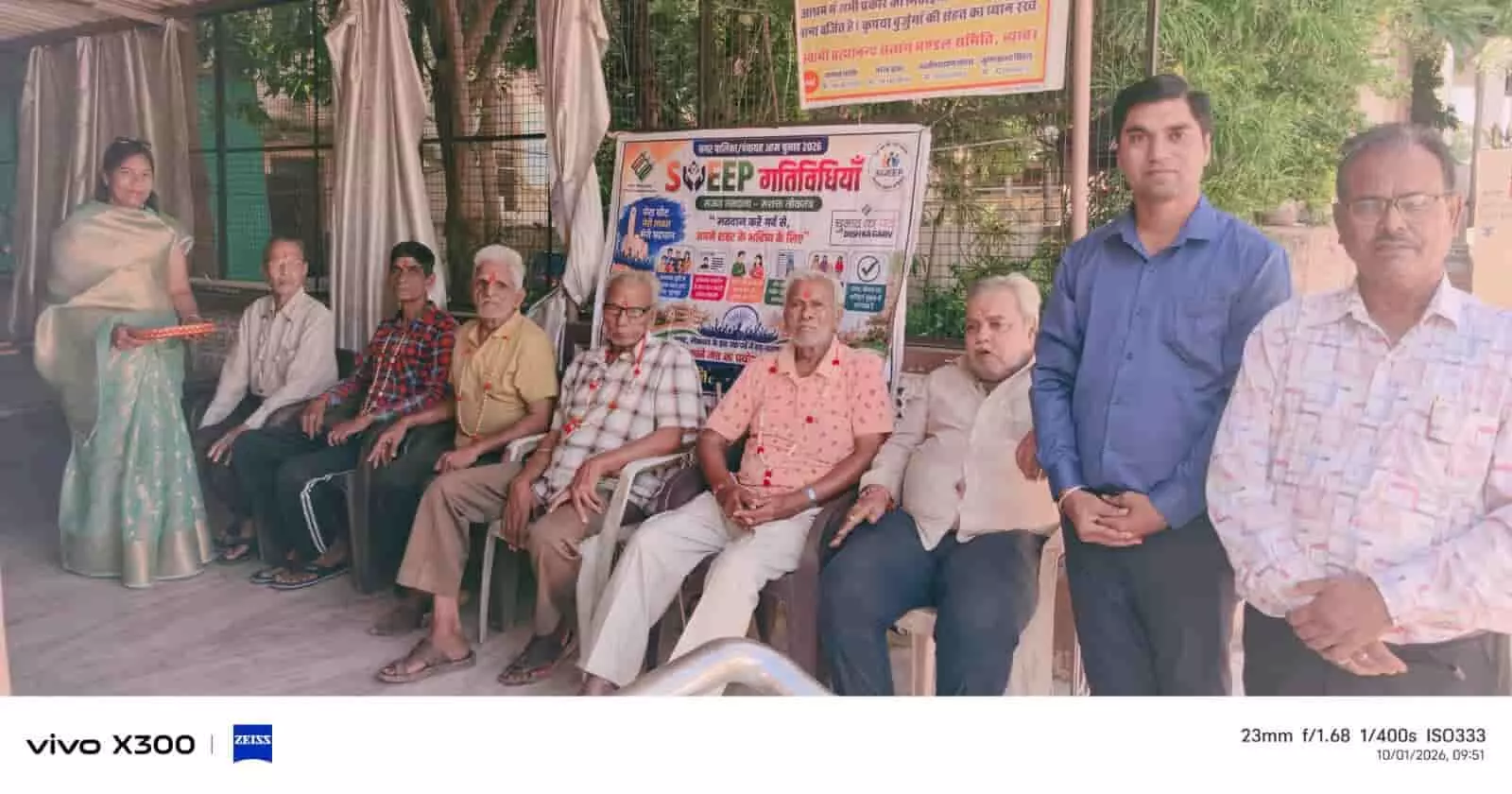 तस्वीर में बाईं से दाईं ओर स्वीप टीम के सदस्य और वृद्धजन बैनर के पास बैठे दिख रहे हैं। तस्वीर में बाईं से दाईं ओर स्वीप टीम के सदस्य और वृद्धजन बैनर के पास बैठे दिख रहे हैं।