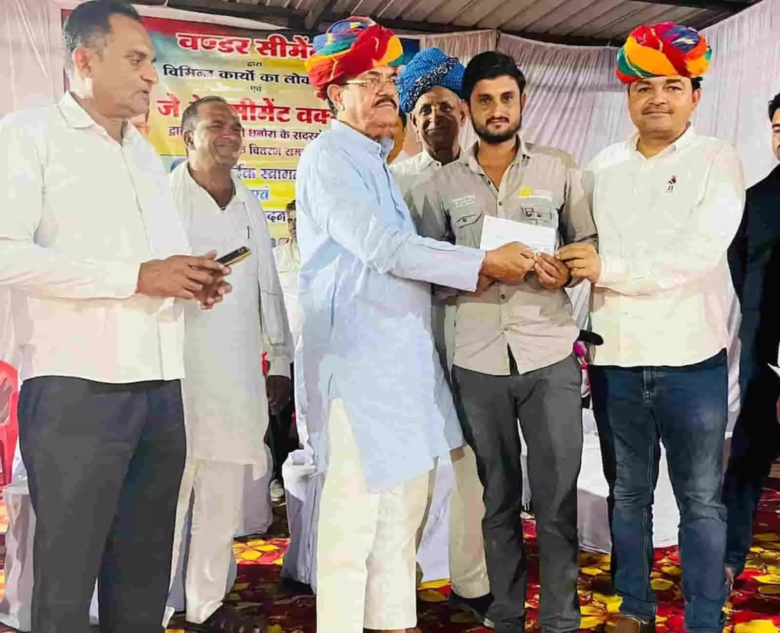 तस्वीर में उदयलाल आंजना और अन्य अतिथि मंच पर एक व्यक्ति को चेक प्रदान करते दिख रहे हैं। तस्वीर में उदयलाल आंजना और अन्य अतिथि मंच पर एक व्यक्ति को चेक प्रदान करते दिख रहे हैं।