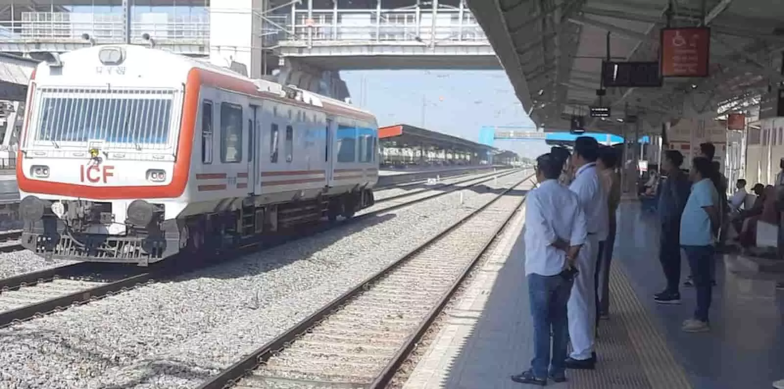 तस्वीर में रेलवे प्लेटफॉर्म पर खड़े अधिकारियों के पास से सफेद और नारंगी रंग की निरीक्षण ट्रेन गुजरती दिख रही है। तस्वीर में रेलवे प्लेटफॉर्म पर खड़े अधिकारियों के पास से सफेद और नारंगी रंग की निरीक्षण ट्रेन गुजरती दिख रही है।