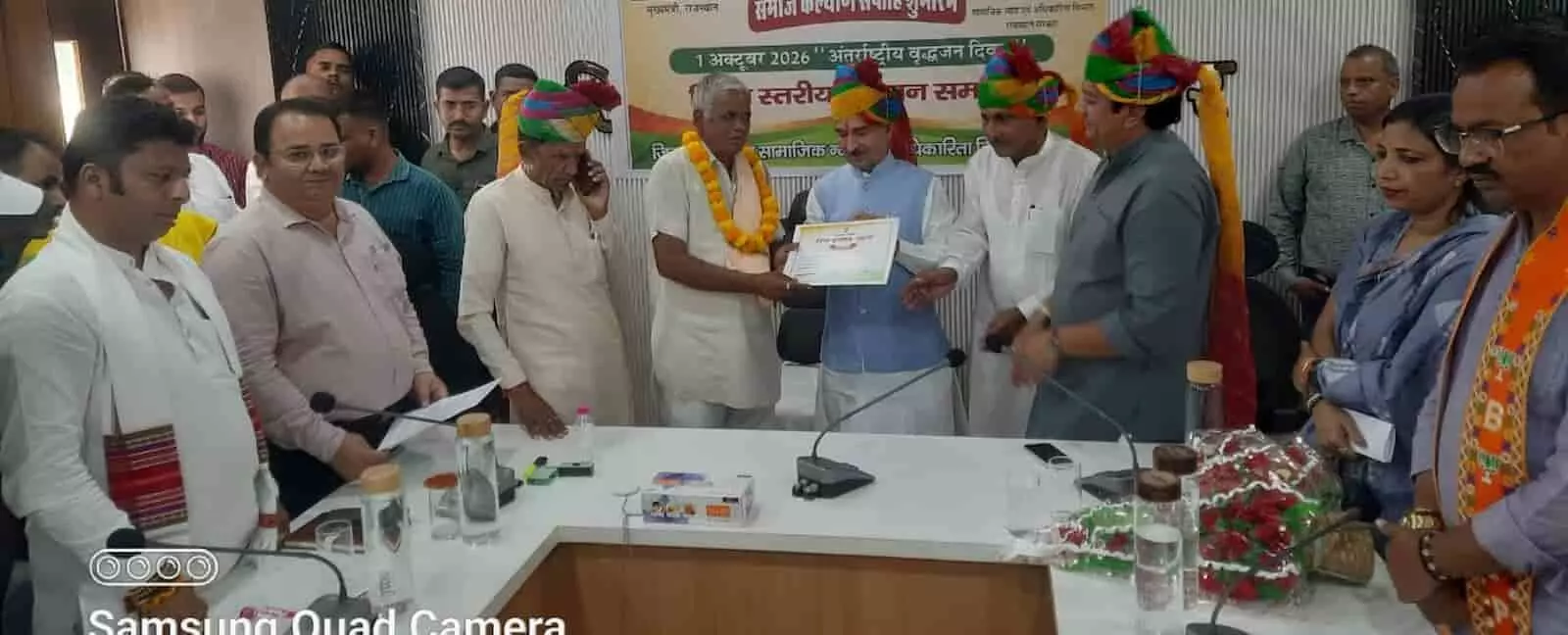 तस्वीर में अतिथि मंच पर एक वृद्ध जन को प्रशस्ति पत्र और माला पहनाकर सम्मानित कर रहे हैं। तस्वीर में अतिथि मंच पर एक वृद्ध जन को प्रशस्ति पत्र और माला पहनाकर सम्मानित कर रहे हैं।