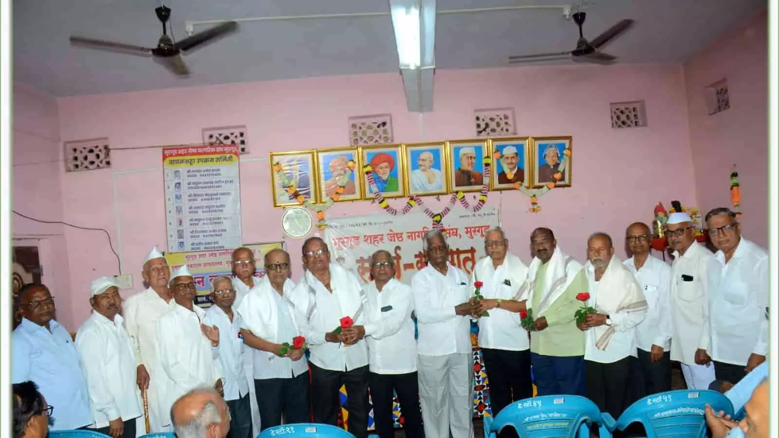 तस्वीर में एक हॉल के भीतर कई वरिष्ठ नागरिक एक कतार में खड़े होकर एक-दूसरे को गुलाब का फूल देते हुए दिख रहे हैं। तस्वीर में एक हॉल के भीतर कई वरिष्ठ नागरिक एक कतार में खड़े होकर एक-दूसरे को गुलाब का फूल देते हुए दिख रहे हैं।