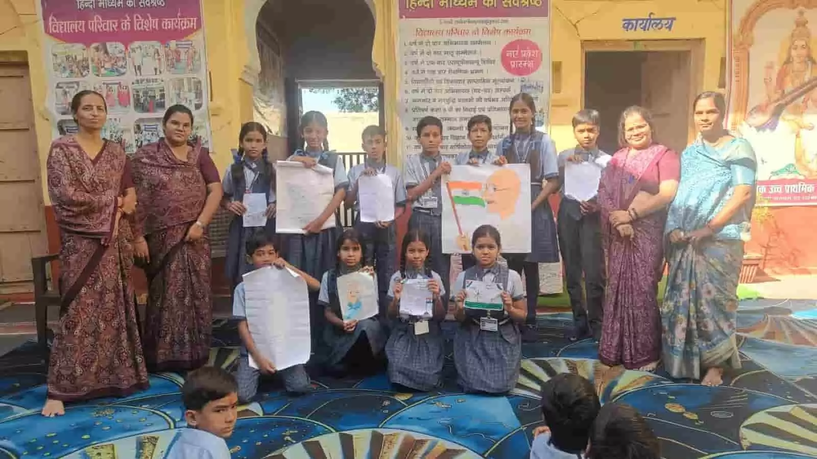 तस्वीर में विद्यालय परिसर में शिक्षक और बच्चे पोस्टर हाथ में लिए खड़े हैं। तस्वीर में विद्यालय परिसर में शिक्षक और बच्चे पोस्टर हाथ में लिए खड़े हैं।