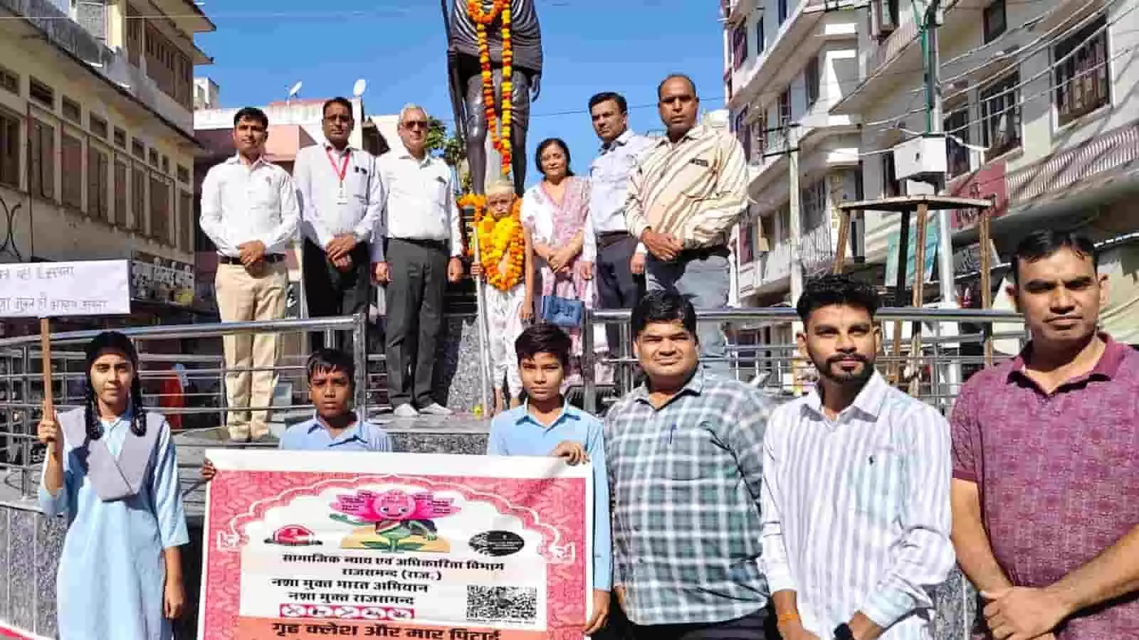 तस्वीर में नशामुक्ति अभियान का बैनर थामे स्कूली बच्चे और महात्मा गांधी की प्रतिमा के पास खड़े अधिकारी दिख रहे हैं। तस्वीर में नशामुक्ति अभियान का बैनर थामे स्कूली बच्चे और महात्मा गांधी की प्रतिमा के पास खड़े अधिकारी दिख रहे हैं।