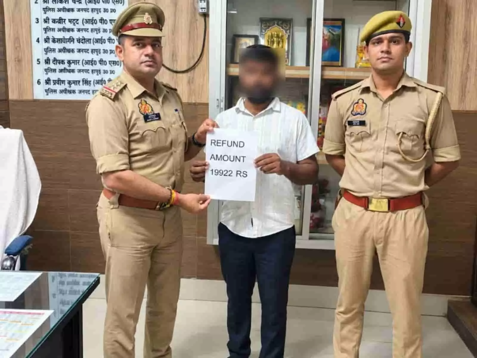 तस्वीर में बाएं से दाएं दो पुलिसकर्मी और बीच में खड़ा व्यक्ति रिफंड लिखा कागज पकड़े हुए हैं। तस्वीर में बाएं से दाएं दो पुलिसकर्मी और बीच में खड़ा व्यक्ति रिफंड लिखा कागज पकड़े हुए हैं।