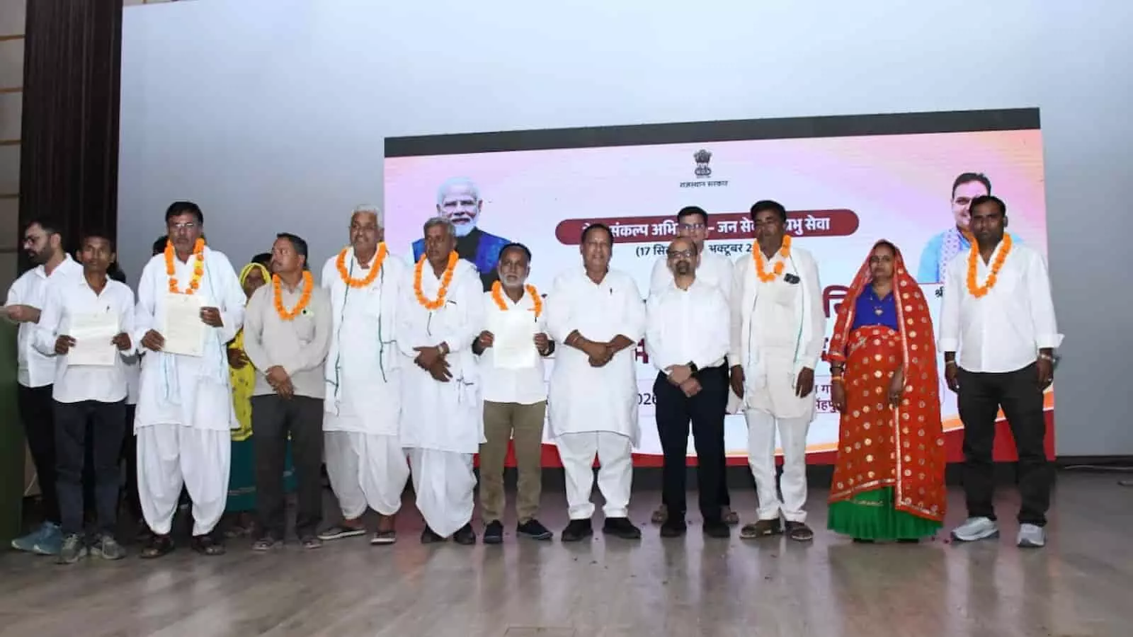 तस्वीर में दिख रही एक पंक्ति में फूलों की माला पहने जनप्रतिनिधि और अधिकारी मंच पर खड़े हैं। तस्वीर में दिख रही एक पंक्ति में फूलों की माला पहने जनप्रतिनिधि और अधिकारी मंच पर खड़े हैं।