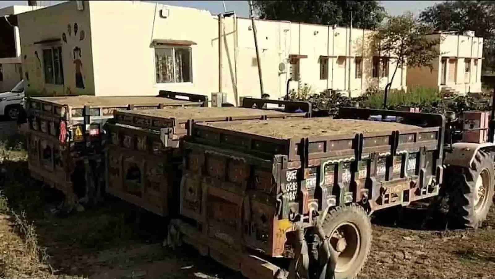 तस्वीर में दिख रही बजरी से भरी ट्रैक्टर-ट्रॉलियां एक इमारत के पास खड़ी हैं। तस्वीर में दिख रही बजरी से भरी ट्रैक्टर-ट्रॉलियां एक इमारत के पास खड़ी हैं।
