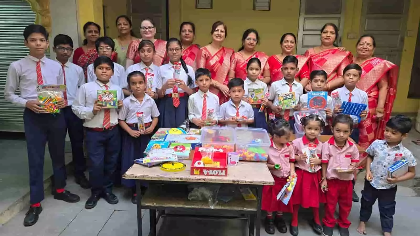 तस्वीर में स्कूली बच्चे हाथों में माइंड गेम्स और स्टेशनरी सामग्री लेकर महिला मंडल की महिलाओं के साथ खड़े हैं। तस्वीर में स्कूली बच्चे हाथों में माइंड गेम्स और स्टेशनरी सामग्री लेकर महिला मंडल की महिलाओं के साथ खड़े हैं।