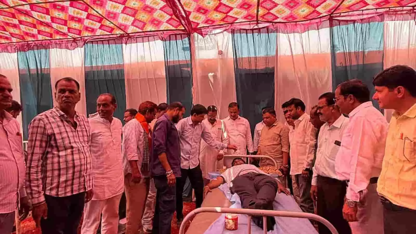 तस्वीर में मंडप के नीचे रक्तदान शिविर के दौरान बेड पर लेटे रक्तदाता के चारों ओर लोग उपस्थित हैं। तस्वीर में मंडप के नीचे रक्तदान शिविर के दौरान बेड पर लेटे रक्तदाता के चारों ओर लोग उपस्थित हैं।