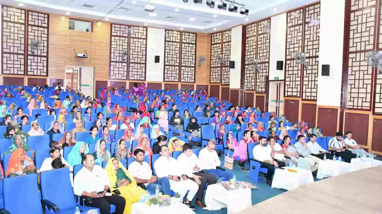 सभागार में नारी शक्ति सम्मेलन के दौरान नीली कुर्सियों पर बैठे लोग और महिलाएं. सभागार में नारी शक्ति सम्मेलन के दौरान नीली कुर्सियों पर बैठे लोग और महिलाएं.