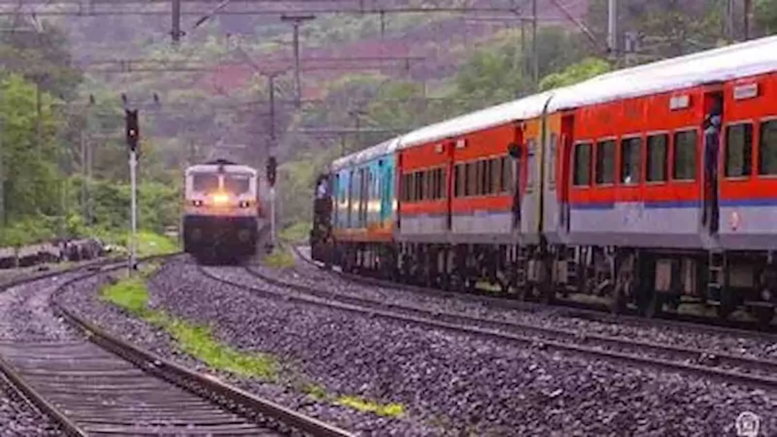 तस्वीर में दिख रही लाल और नीले रंग की पैसेंजर ट्रेन पटरियों पर चलती हुई नजर आ रही है। तस्वीर में दिख रही लाल और नीले रंग की पैसेंजर ट्रेन पटरियों पर चलती हुई नजर आ रही है।