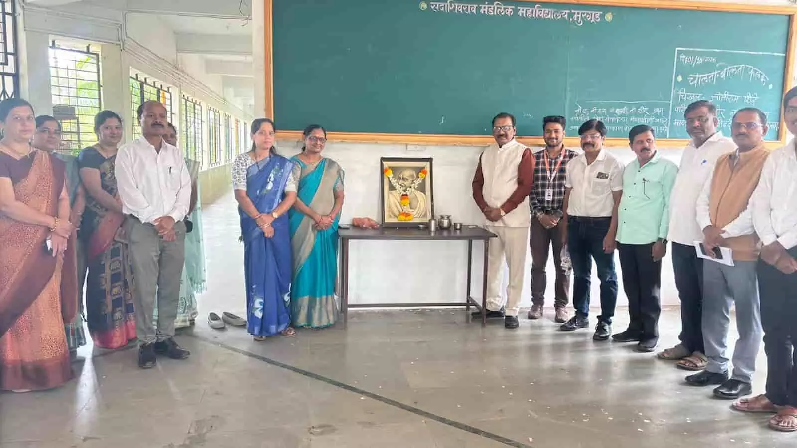 महात्मा गांधी की प्रतिमा के पास खड़े कॉलेज के प्राचार्य और प्राध्यापक। महात्मा गांधी की प्रतिमा के पास खड़े कॉलेज के प्राचार्य और प्राध्यापक।