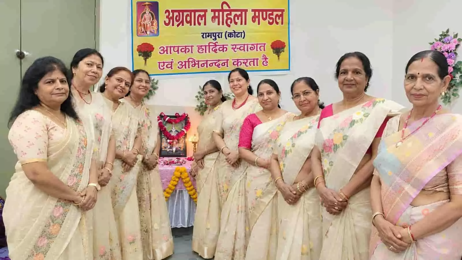 तस्वीर में दिख रही महिलाएं पारंपरिक साड़ी पहने बैनर के समक्ष पंक्तिबद्ध खड़ी हैं। तस्वीर में दिख रही महिलाएं पारंपरिक साड़ी पहने बैनर के समक्ष पंक्तिबद्ध खड़ी हैं।