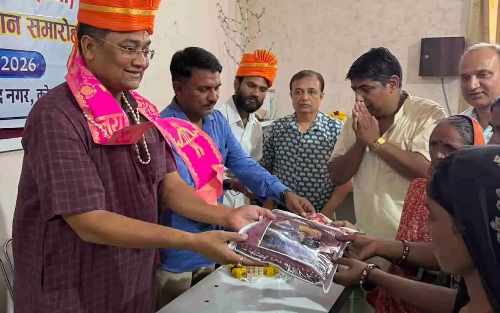 तस्वीर में बाईं ओर साफा पहने अतिथि बुजुर्ग महिला को पैकेट भेंट कर रहे हैं और पास खड़े अन्य अतिथि हाथ जोड़कर खड़े हैं। तस्वीर में बाईं ओर साफा पहने अतिथि बुजुर्ग महिला को पैकेट भेंट कर रहे हैं और पास खड़े अन्य अतिथि हाथ जोड़कर खड़े हैं।