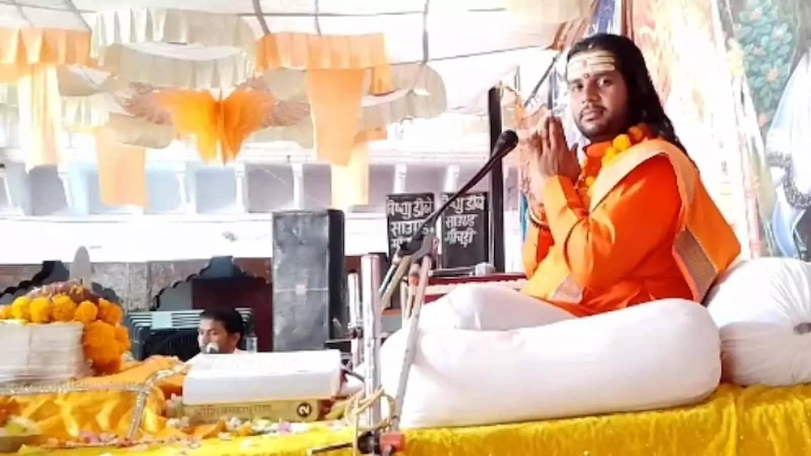 तस्वीर में भगवा वस्त्र धारण किए कथा वाचक व्यासपीठ पर हाथ जोड़कर प्रणाम की मुद्रा में बैठे हैं। तस्वीर में भगवा वस्त्र धारण किए कथा वाचक व्यासपीठ पर हाथ जोड़कर प्रणाम की मुद्रा में बैठे हैं।