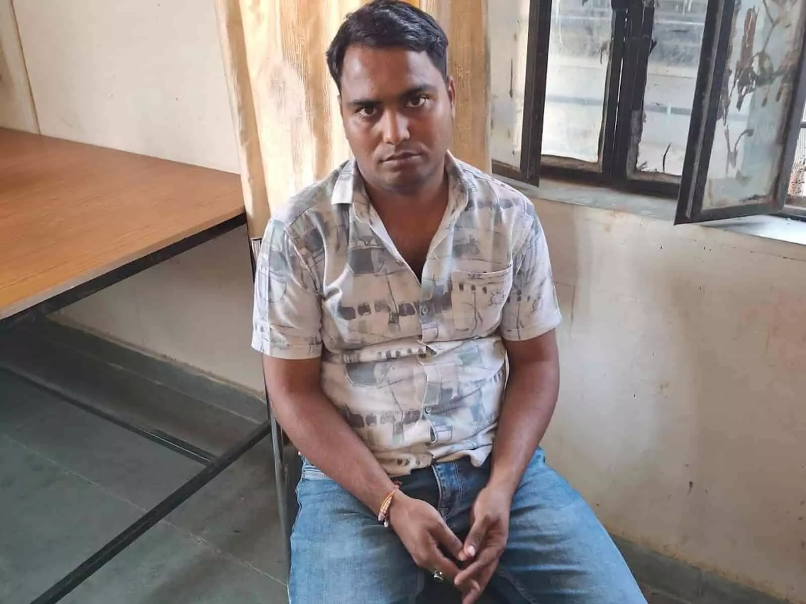 तस्वीर में दिख रही खिड़की के पास कुर्सी पर बैठा एक व्यक्ति कैमरे की ओर देख रहा है। तस्वीर में दिख रही खिड़की के पास कुर्सी पर बैठा एक व्यक्ति कैमरे की ओर देख रहा है।