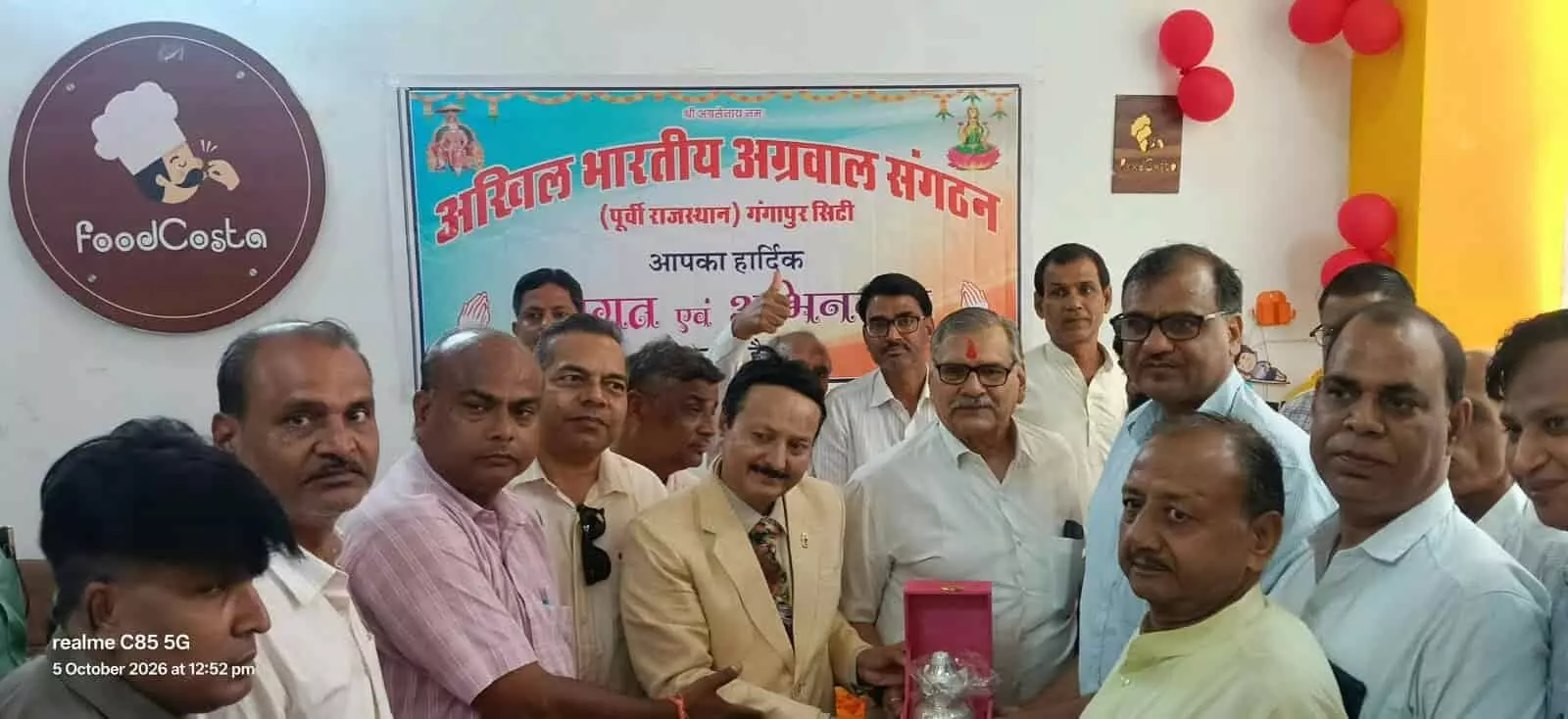 तस्वीर में एक कमरे में बैनर के आगे स्वागत समारोह के दौरान कई पुरुष खड़े दिख रहे हैं। तस्वीर में एक कमरे में बैनर के आगे स्वागत समारोह के दौरान कई पुरुष खड़े दिख रहे हैं।