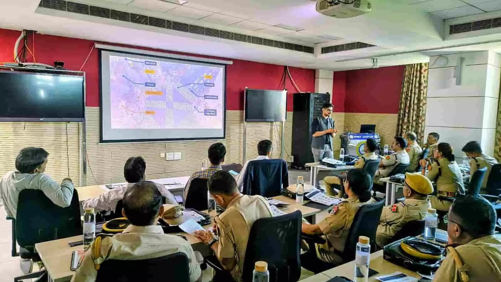 तस्वीर में पुलिस अधिकारी एक कमरे में बैठकर प्रोजेक्टर स्क्रीन पर चल रही प्रेजेंटेशन को देख रहे हैं। तस्वीर में पुलिस अधिकारी एक कमरे में बैठकर प्रोजेक्टर स्क्रीन पर चल रही प्रेजेंटेशन को देख रहे हैं।