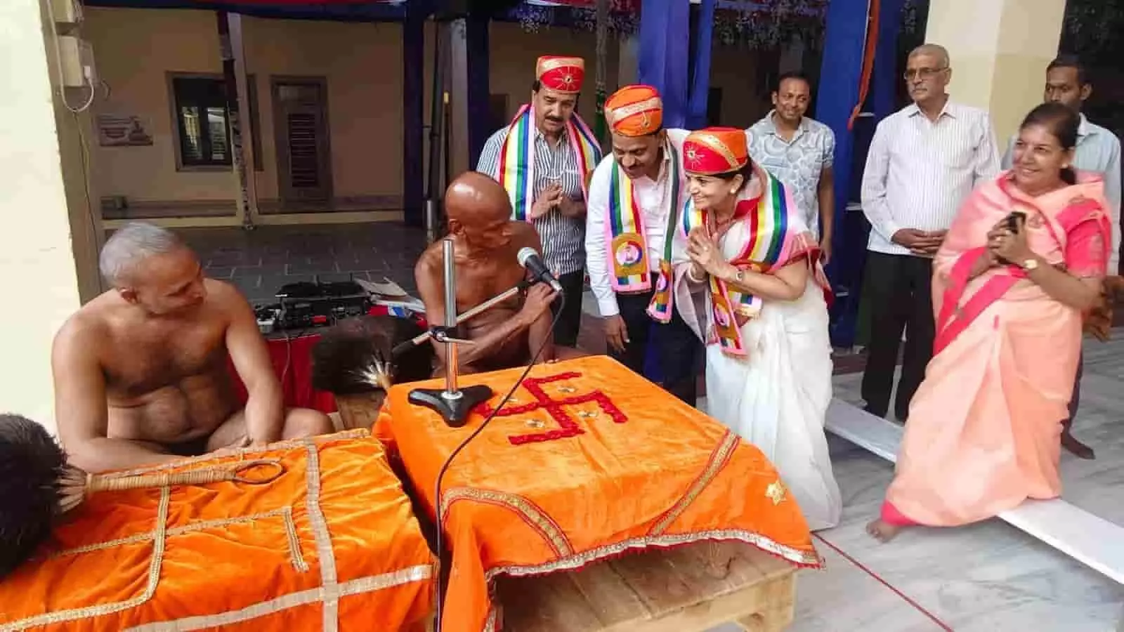 तस्वीर में बाएं से दाएं जैन मुनि, पारंपरिक पोशाक में नमन करते श्रद्धालु और अन्य लोग दिख रहे हैं। तस्वीर में बाएं से दाएं जैन मुनि, पारंपरिक पोशाक में नमन करते श्रद्धालु और अन्य लोग दिख रहे हैं।