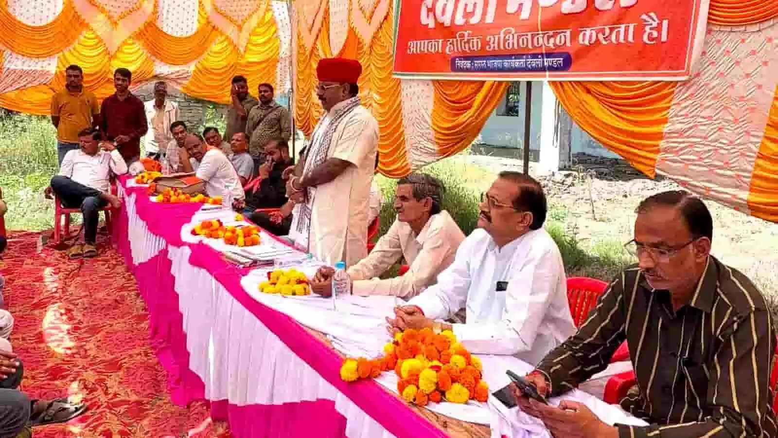 तस्वीर में दिख रही एक चुनावी बैठक के दौरान मंच पर लोग बैठे और खड़े नजर आ रहे हैं। तस्वीर में दिख रही एक चुनावी बैठक के दौरान मंच पर लोग बैठे और खड़े नजर आ रहे हैं।