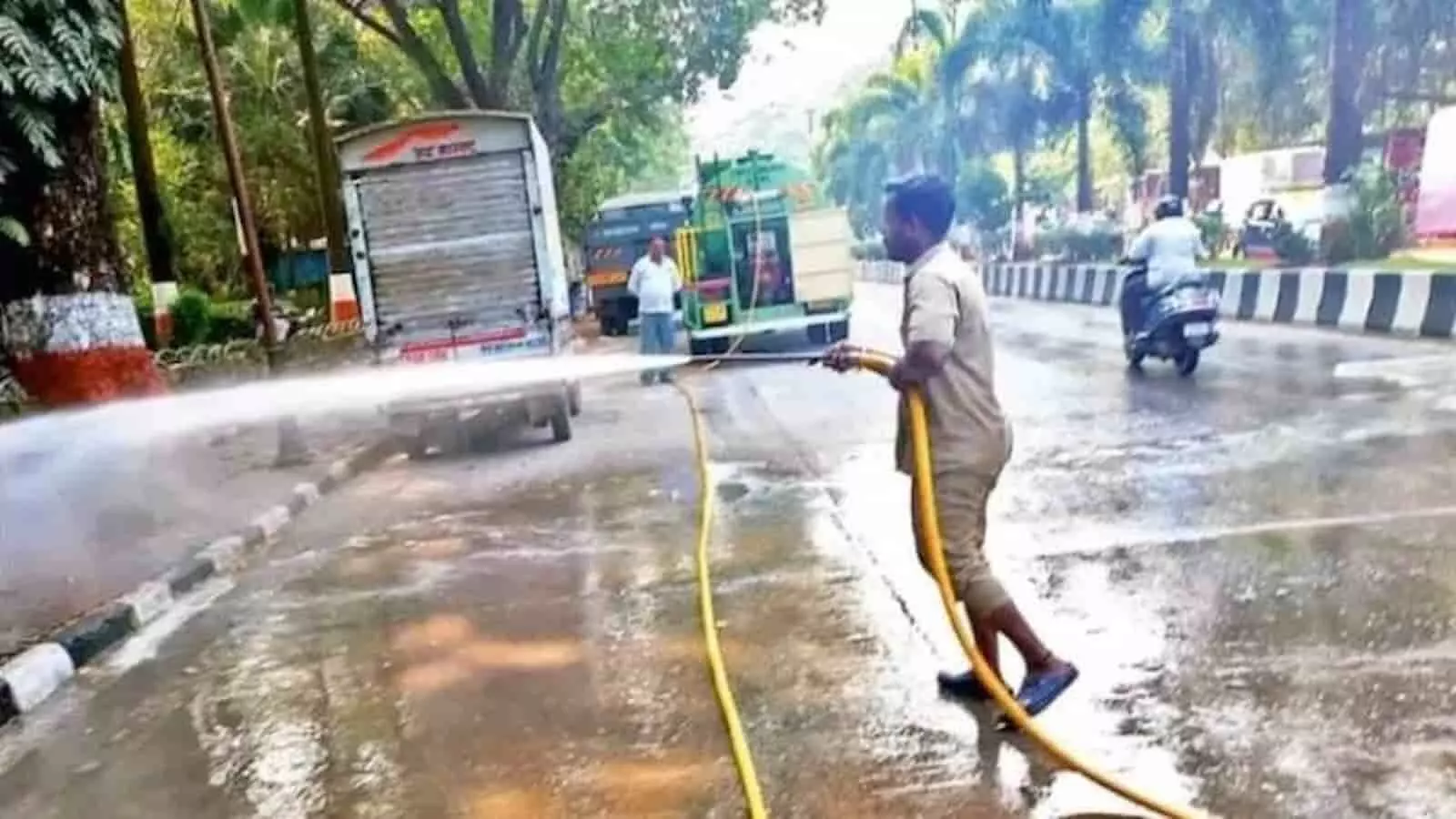 सड़क पर खड़ा कर्मचारी हाई प्रेशर वाटर पाइप से मुंबई की मुख्य सड़क को धो रहा है। सड़क पर खड़ा कर्मचारी हाई प्रेशर वाटर पाइप से मुंबई की मुख्य सड़क को धो रहा है।